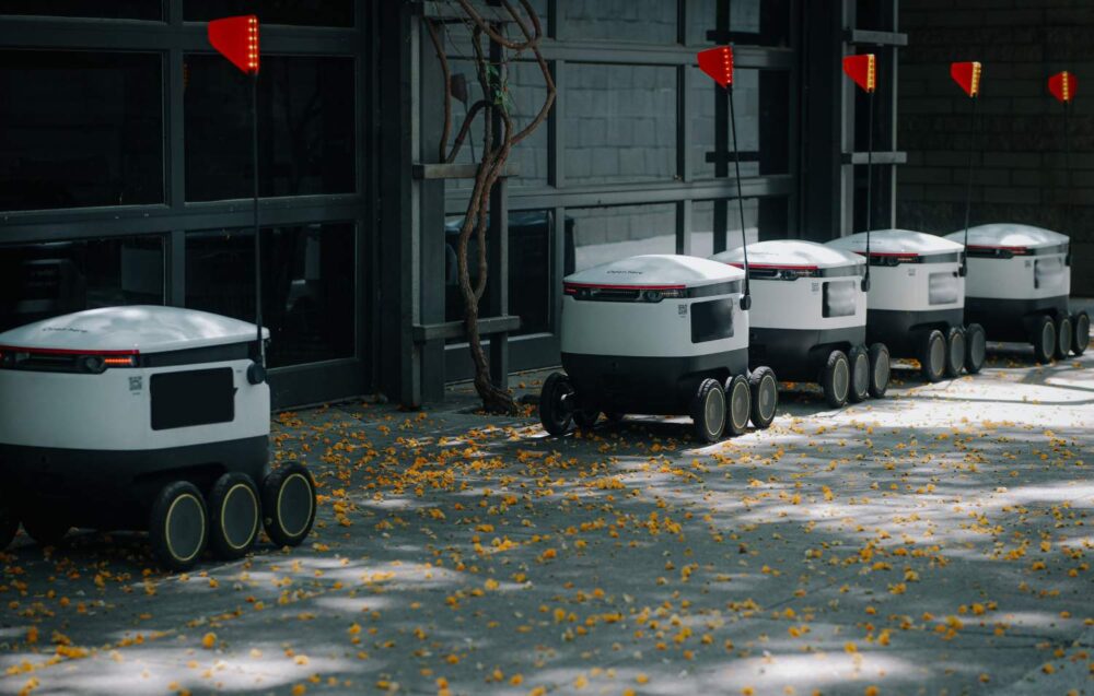an image showing delivery robots waiting in a line on a city street