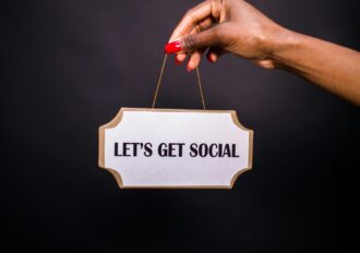 handing holding a wooden sign that says let's get social