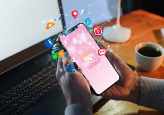 a person holding a smartphone with social media icons floating out of the screen